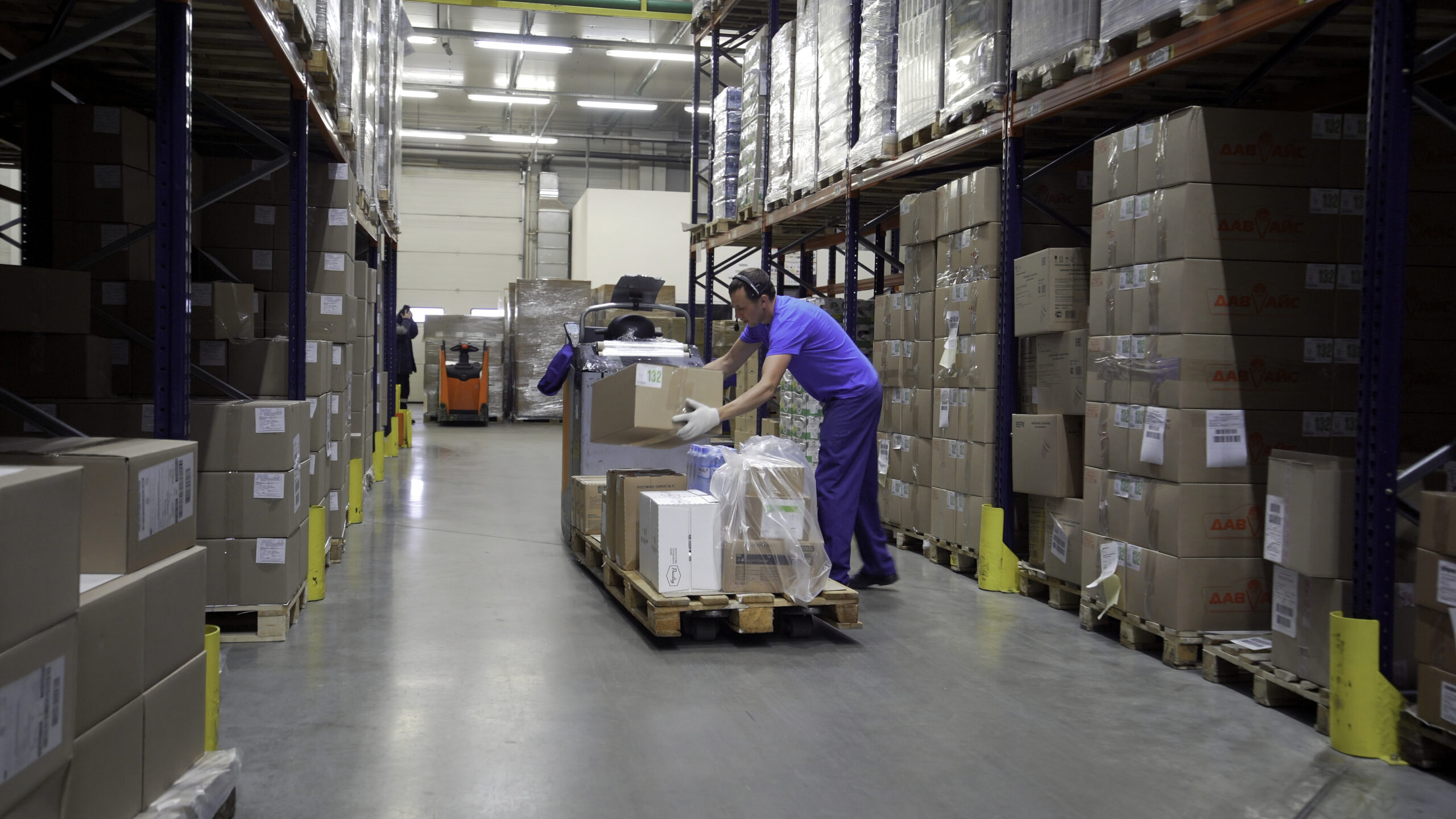 A huge room for a warehouse. Creative. Huge parcels next to which specially equipped cars drive and deliver these orders. High quality 4k footage